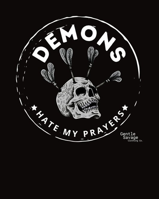 Black and white graphic with skull, arrows, and text 'DEMONS HATE MY PRAYERS' on a black background.