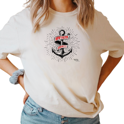 Person wearing a beige t-shirt with an anchor graphic and text.